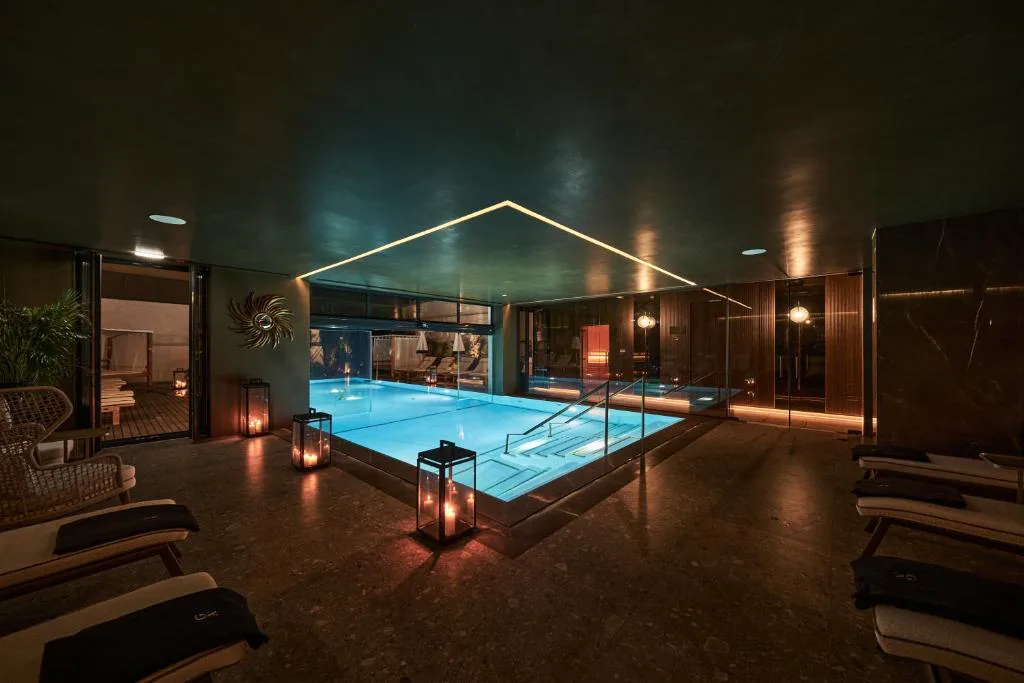 Piscina cubierta iluminada por la noche con velas y tumbonas, GA Palace