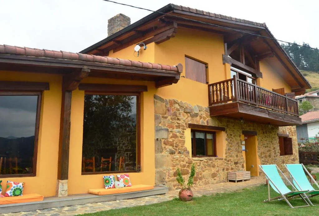 Casa amarilla y de piedra con balcón de madera