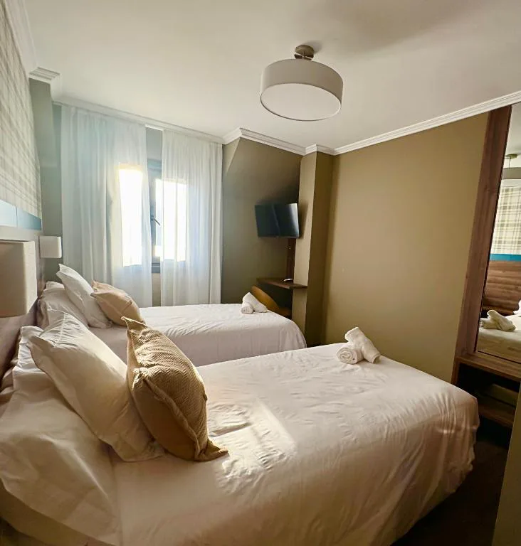 Dormitorio con dos camas, cabecero acolchado y cojines beige, Hotel SPA GBC Arcade