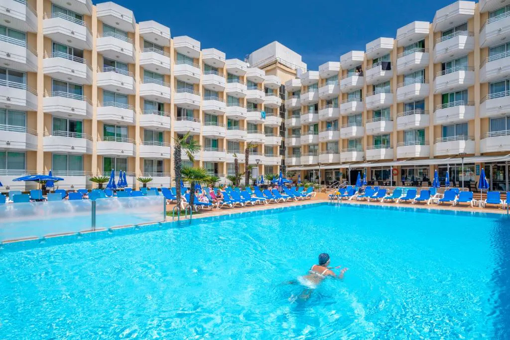 Piscina grande con bañistas frente al edificio del hotel