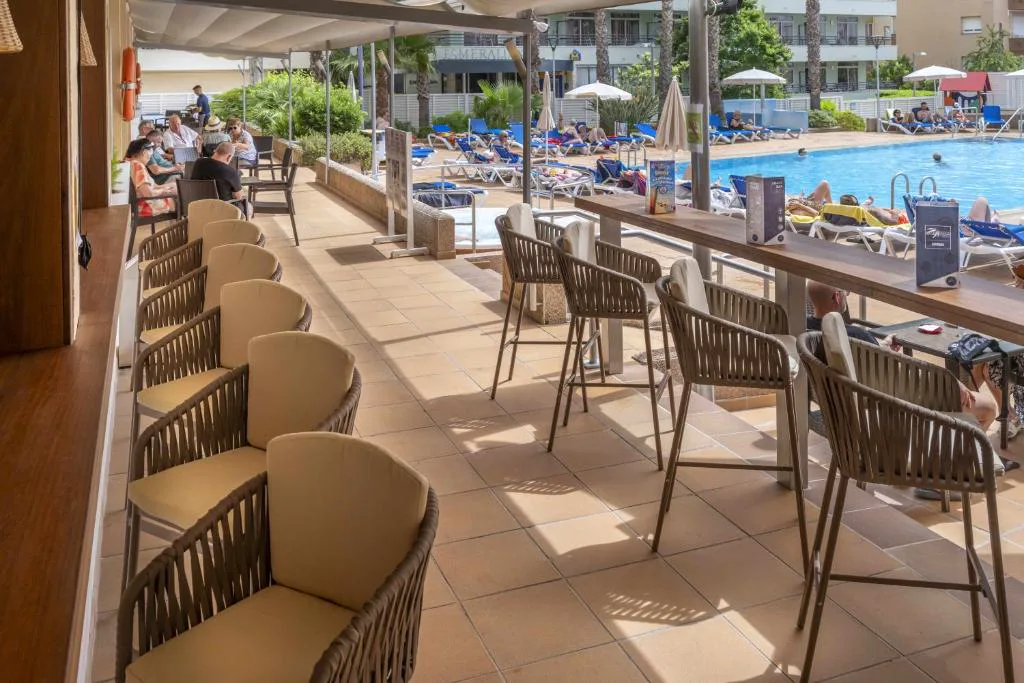 Terraza con mesas frente a la piscina