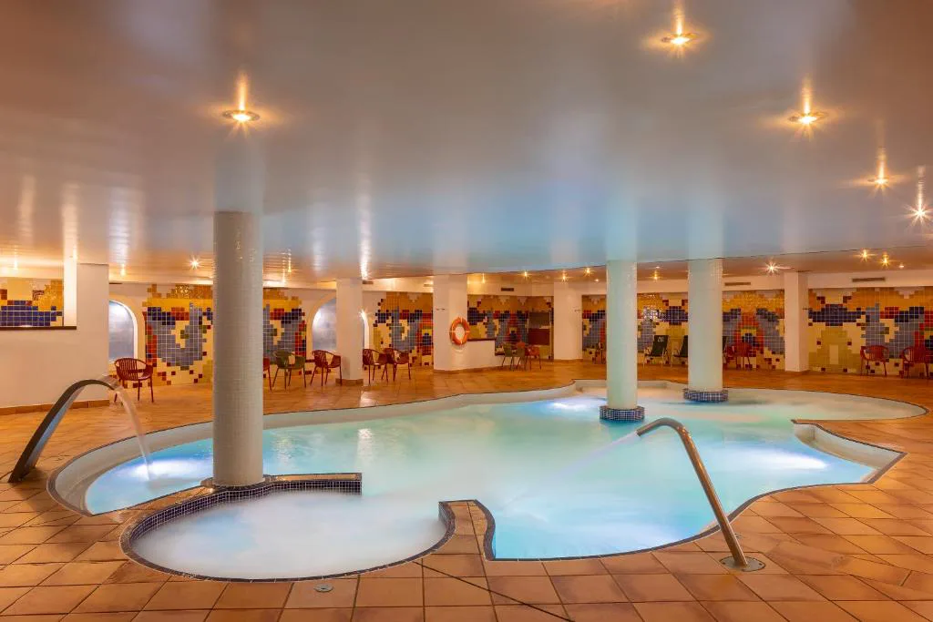Piscina cubierta de spa con columnas y zona de hidromasaje