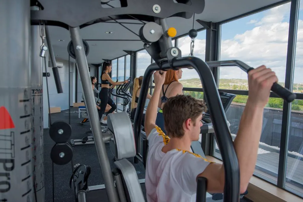 Gimnasio con máquinas junto a un ventanal