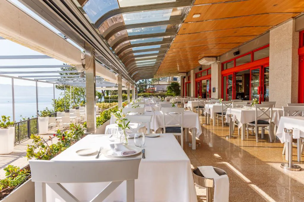 Terraza acristalada del restaurante con mesas vestidas y vistas al mar, Gran Talaso Hotel Sanxenxo