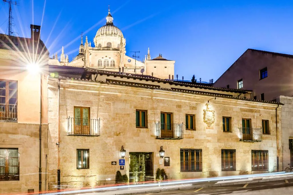 Fachada iluminada de noche del palacio del Grand Hotel Don Gregorio con una cúpula al fondo