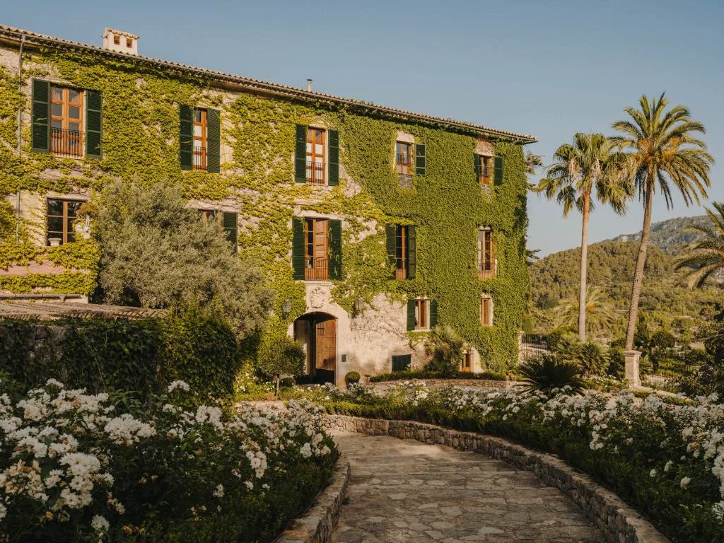 Fachada del palacio cubierta de hiedra con acceso empedrado, Grand Hotel Son Net
