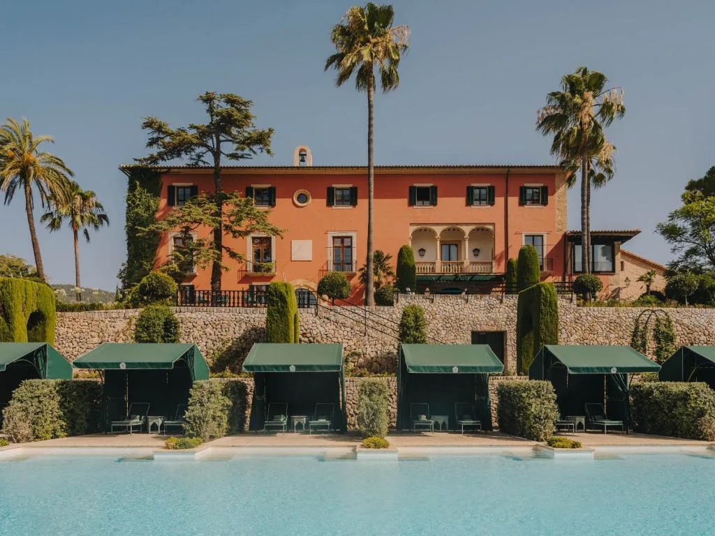 Fachada terracota del palacio con cabañas privadas junto a la piscina, Grand Hotel Son Net