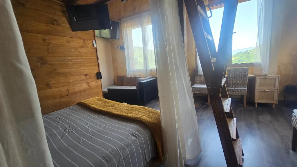 Dormitorio abuhardillado con estructura de madera vista en Granja Paraíso