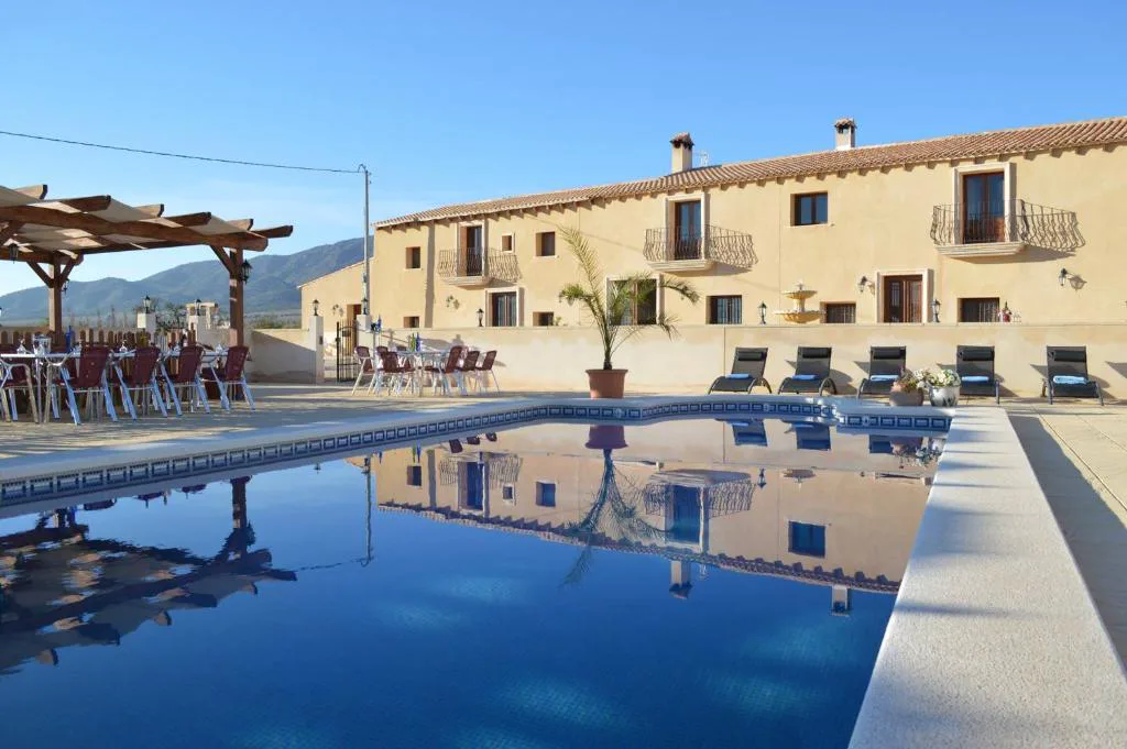Piscina larga junto a la fachada de piedra de la casa rural