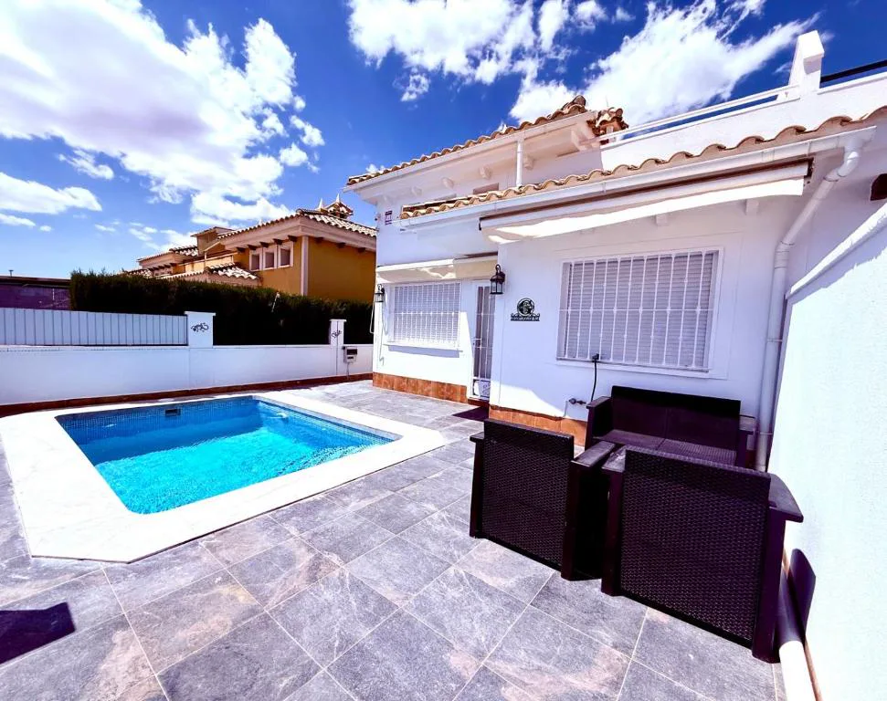 Piscina privada con sillones de exterior en un patio blanco