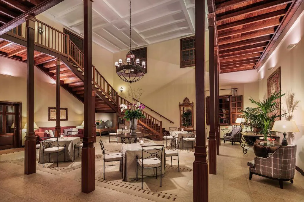 Lobby colonial con columnas de madera, escalera y lámpara de araña, Hacienda del Conde