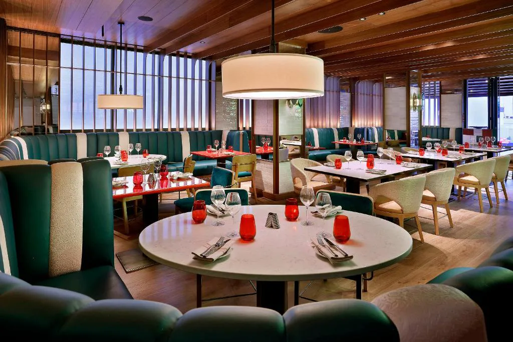 Restaurante con sillones verdes y mesas redondas rojas