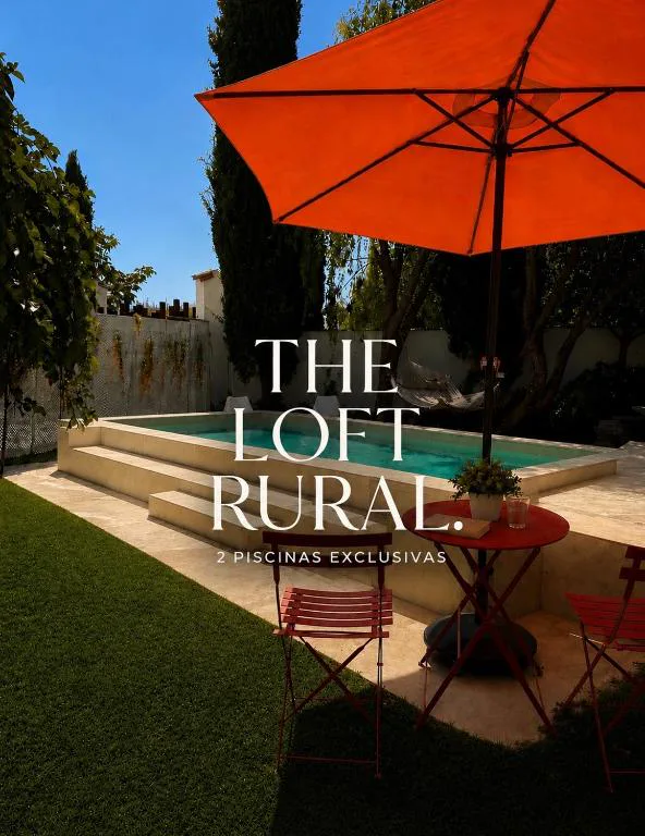 Piscina de escalones con sombrilla naranja y cartel The Loft Rural