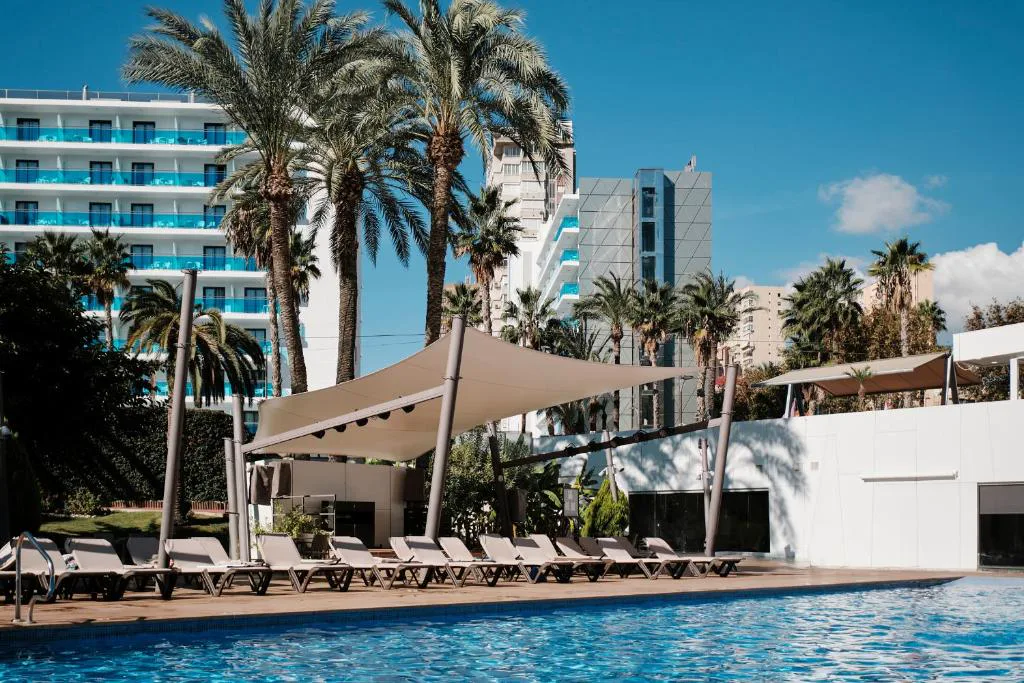 Piscina con toldos y tumbonas frente a los rascacielos de Benidorm