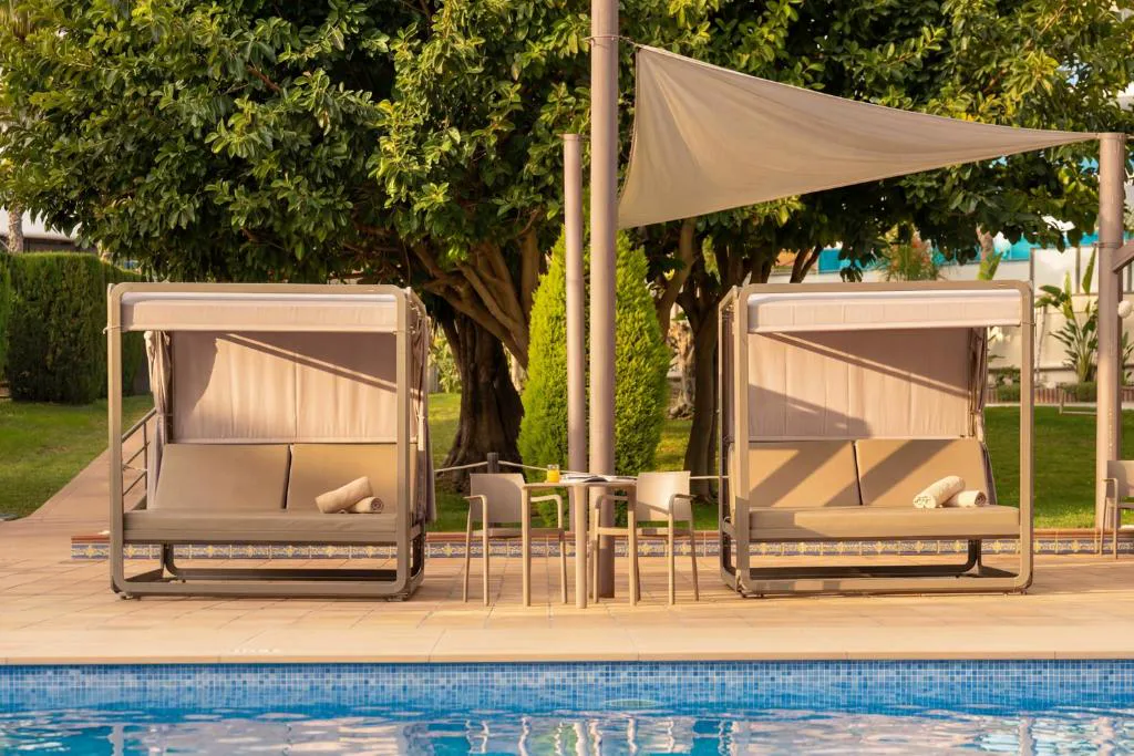 Camas balinesas con toldo junto a la piscina