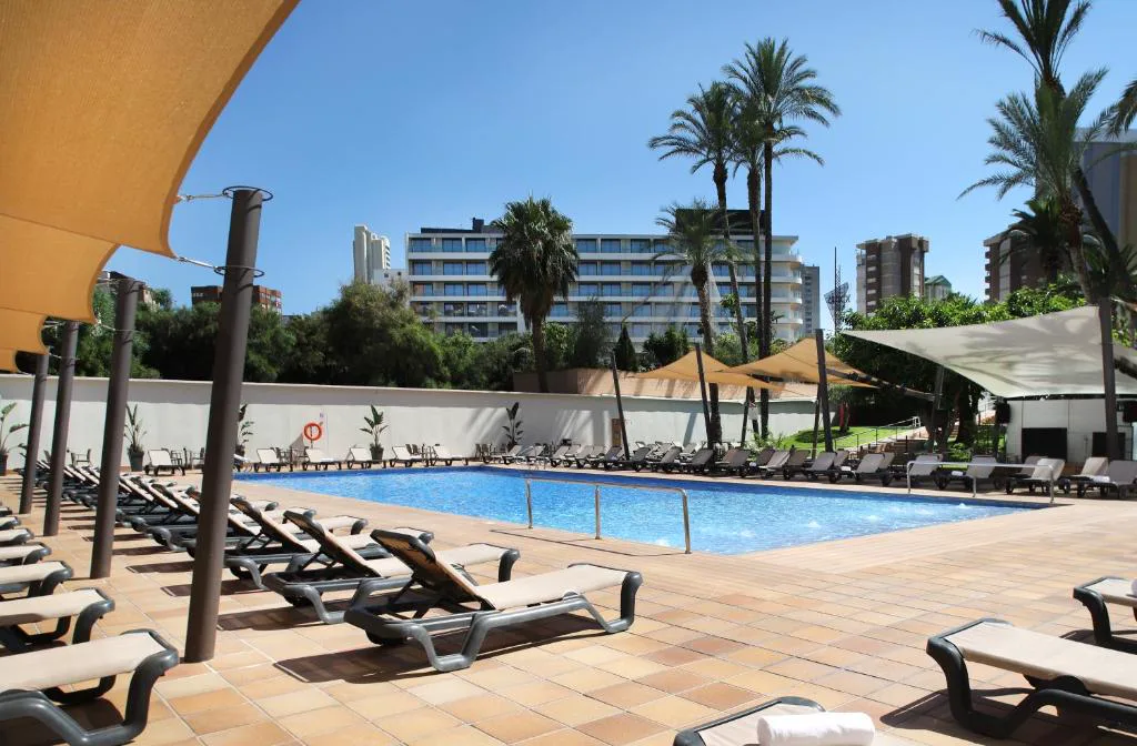 Piscina con tumbonas y palmeras junto al hotel