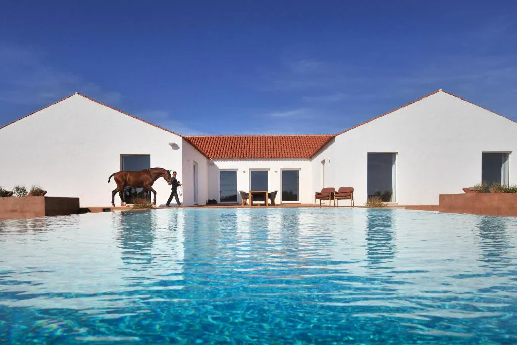 Casa tradicional alentejana con piscina y un caballo lusitano junto al agua, Herdade da Malhadinha Nova