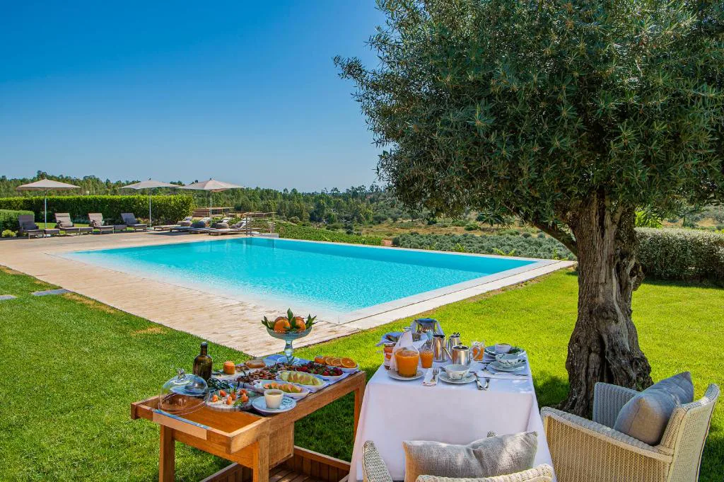 Desayuno servido junto a la piscina bajo un olivo centenario, Herdade da Malhadinha Nova