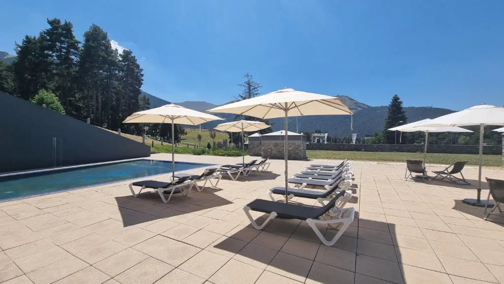 Piscina exterior con tumbonas y sombrillas