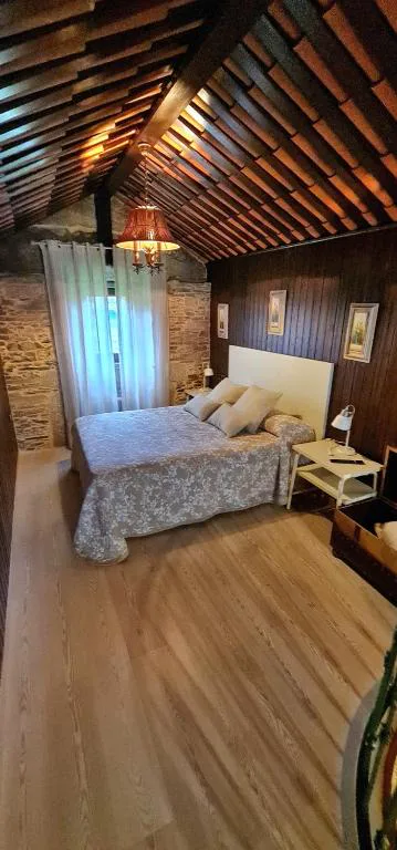 Dormitorio abuhardillado con techo de tejas visto y paredes de piedra, Hórreo Lar San Adrián