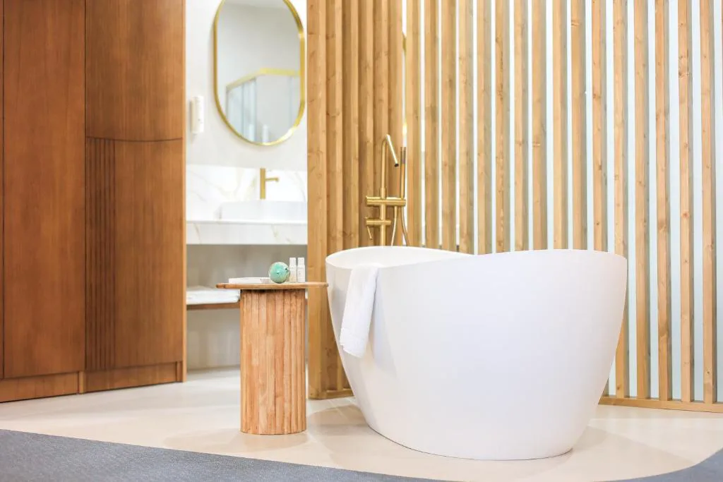 Baño con bañera exenta blanca y paneles de bambú