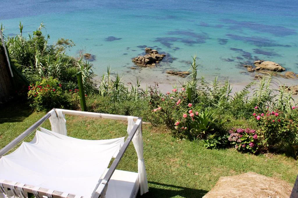 Terraza con mesa y silla blanca sobre el césped junto al mar, Hostal Casa Aurita Adults Only