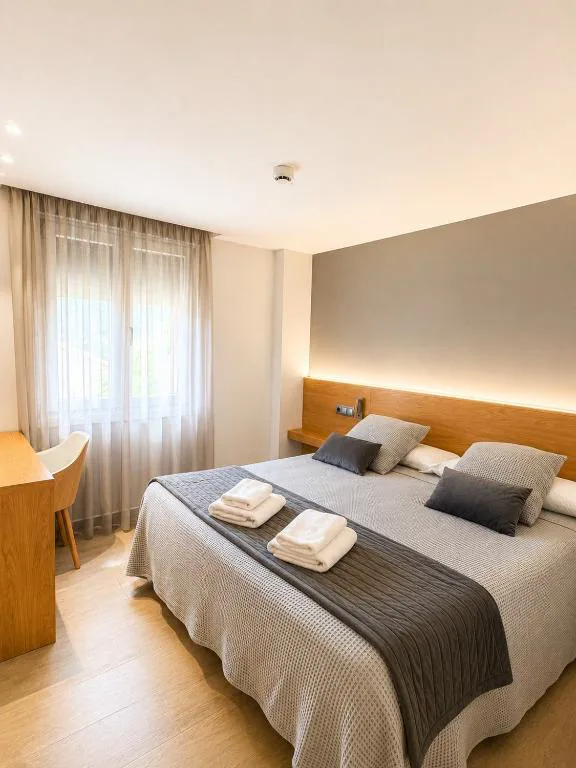 Habitación con cabecero de madera y ropa de cama gris