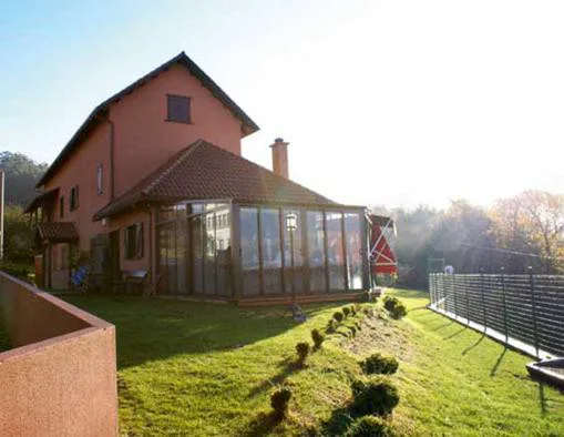 Fachada de la casa tradicional gallega con jardín y porche acristalado, Hostal Meson Leira Antiga