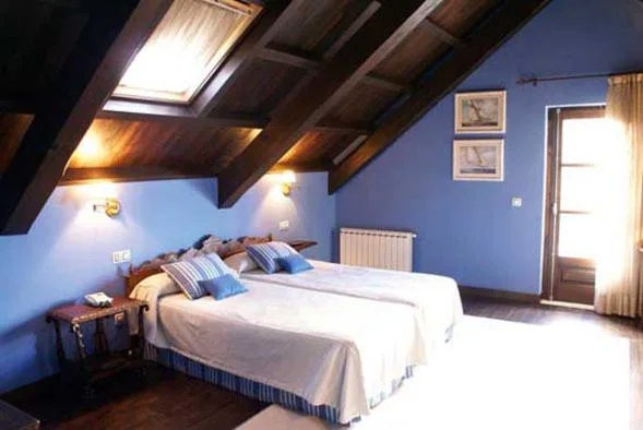Habitación abuhardillada en tonos azules con vigas de madera vista, Hostal Meson Leira Antiga