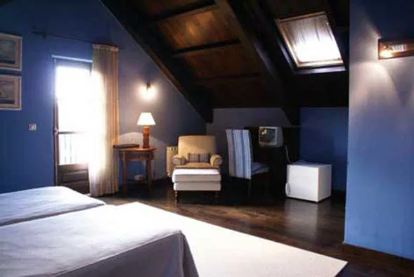 Habitación abuhardillada con sillón de lectura junto a la ventana, Hostal Meson Leira Antiga