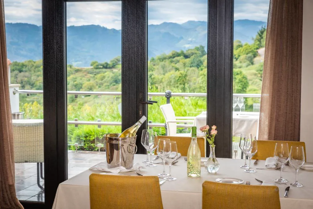 Mesa del restaurante con copas de vino y vistas al valle en Hosteria de Torazo