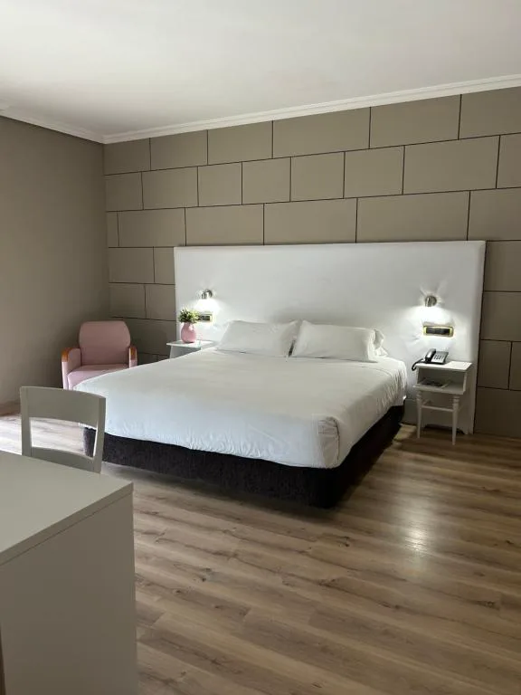Habitación doble con sillón rosa y cabecero blanco, Hotel Alfonso I