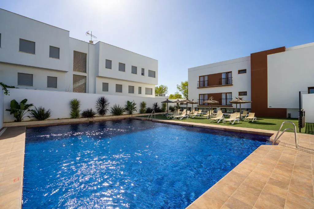 Piscina rodeada de edificios blancos y césped