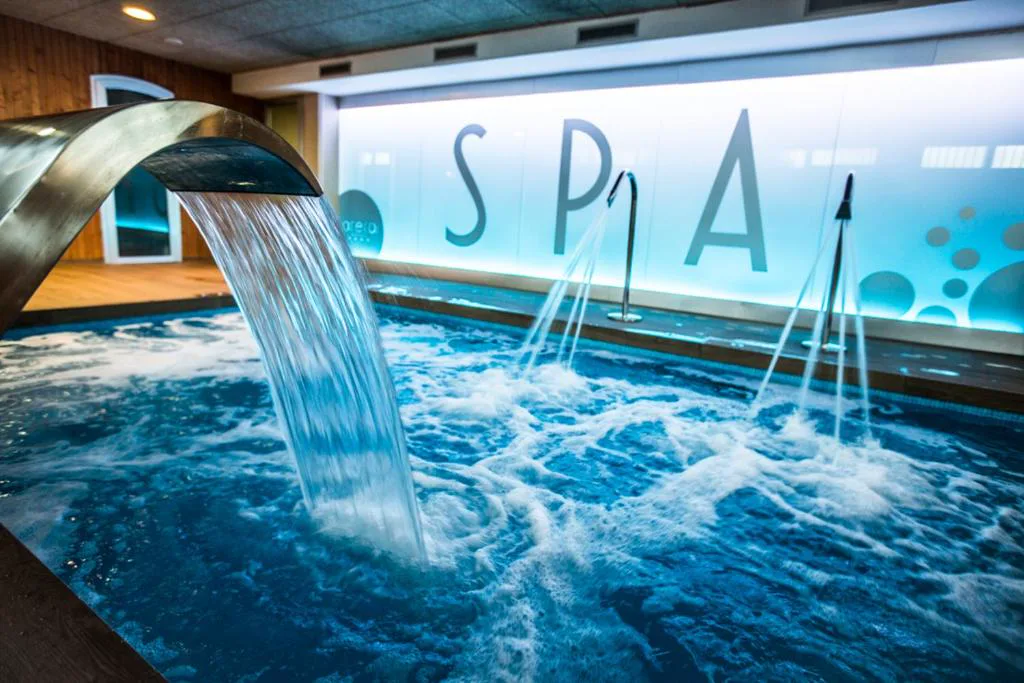 Piscina de hidromasaje del spa con chorro de agua cayendo
