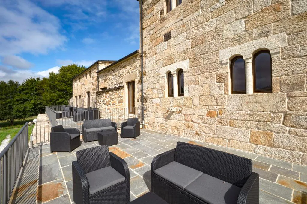Terraza con sofás de exterior junto a la fachada de piedra del pazo, Hotel As Torres da Hermida