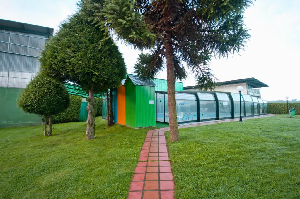Jardín con árboles junto al pabellón acristalado de la piscina, Hotel Auditorio Santiago & Spa