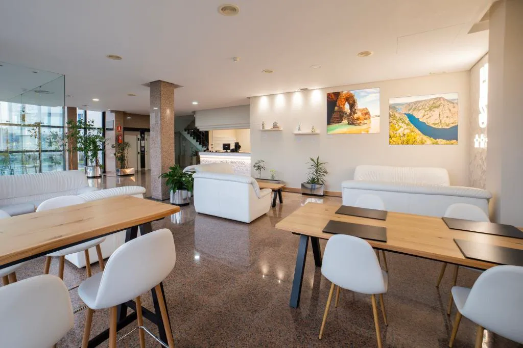 Recepción y zona de estar con sofás blancos y suelo de granito, Hotel Auditorio Santiago & Spa