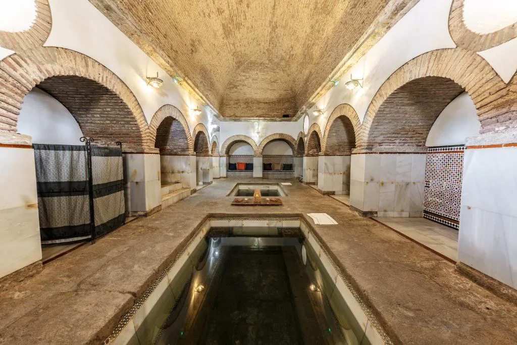 Sala de baños con arcos de ladrillo y una piscina termal alargada