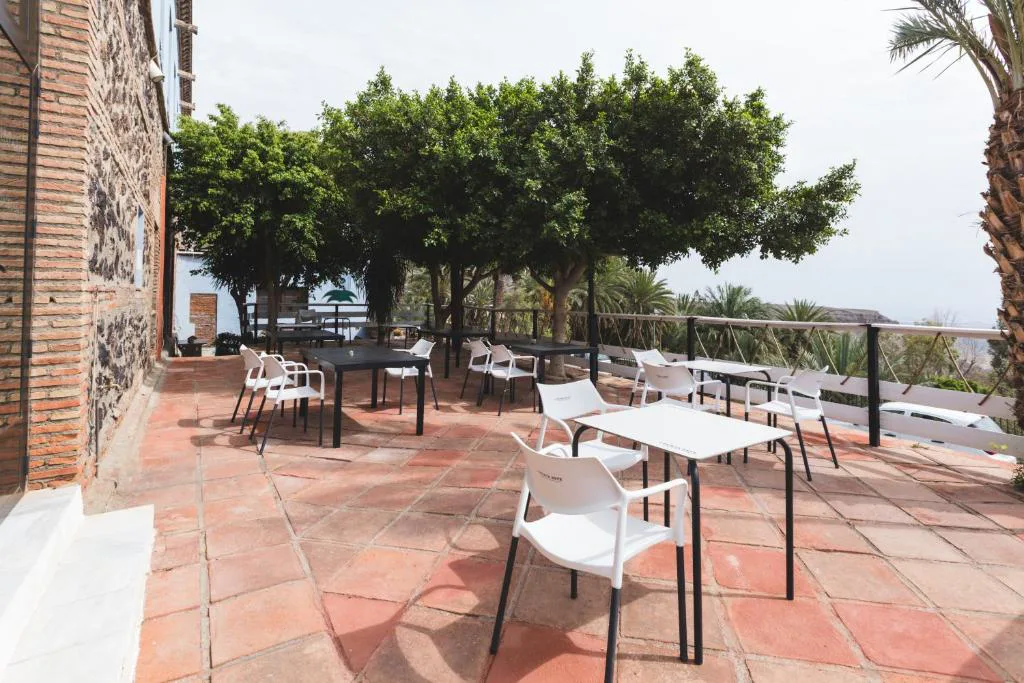 Terraza con mesas bajo árboles y vistas al valle