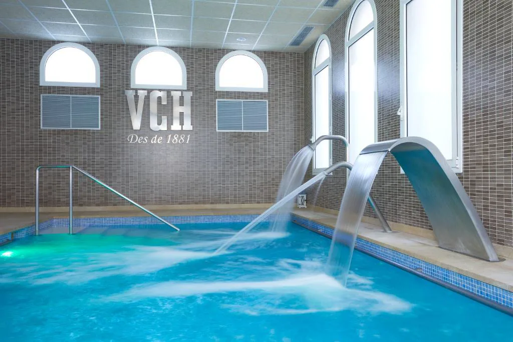 Piscina termal cubierta con chorros de agua y arcos blancos