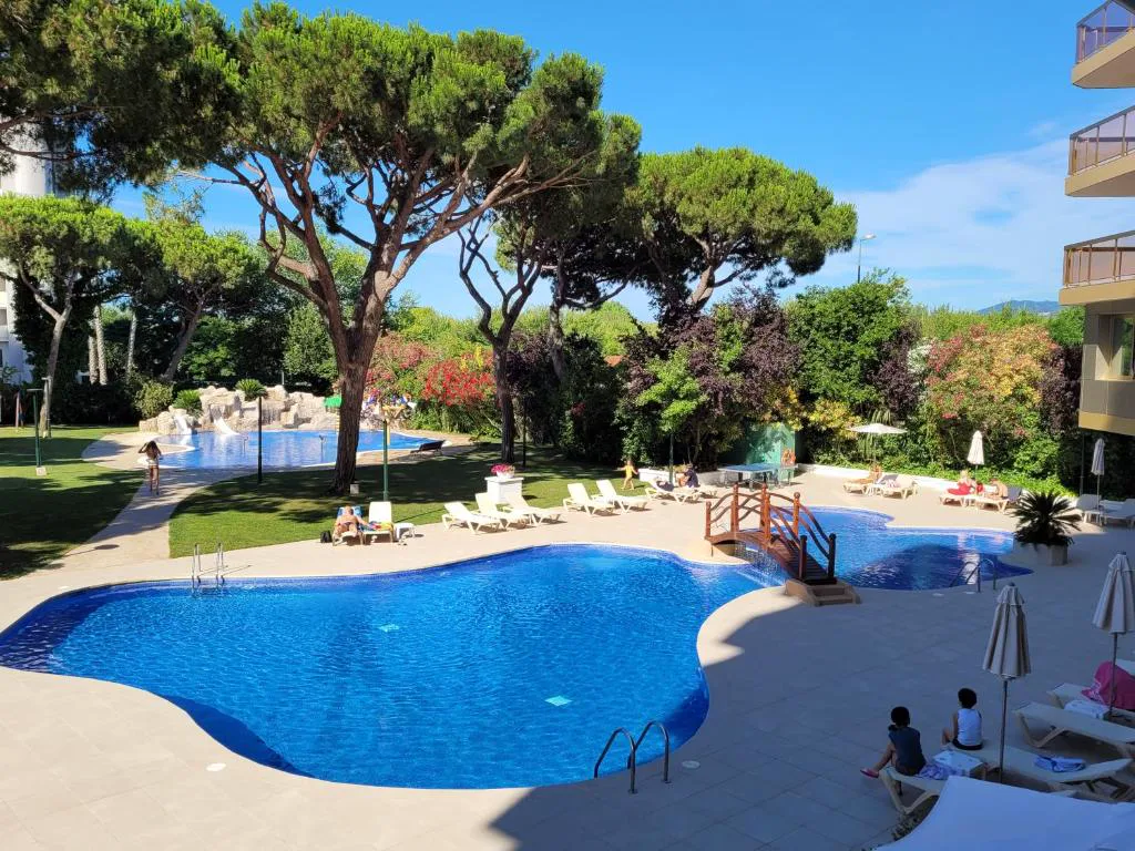 Piscina entre pinos y jardín junto al hotel