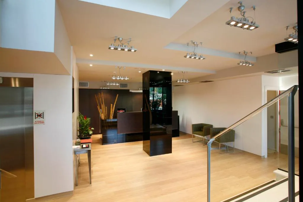 Recepción moderna con columna oscura y sillones verdes, Hotel Bienestar Moaña