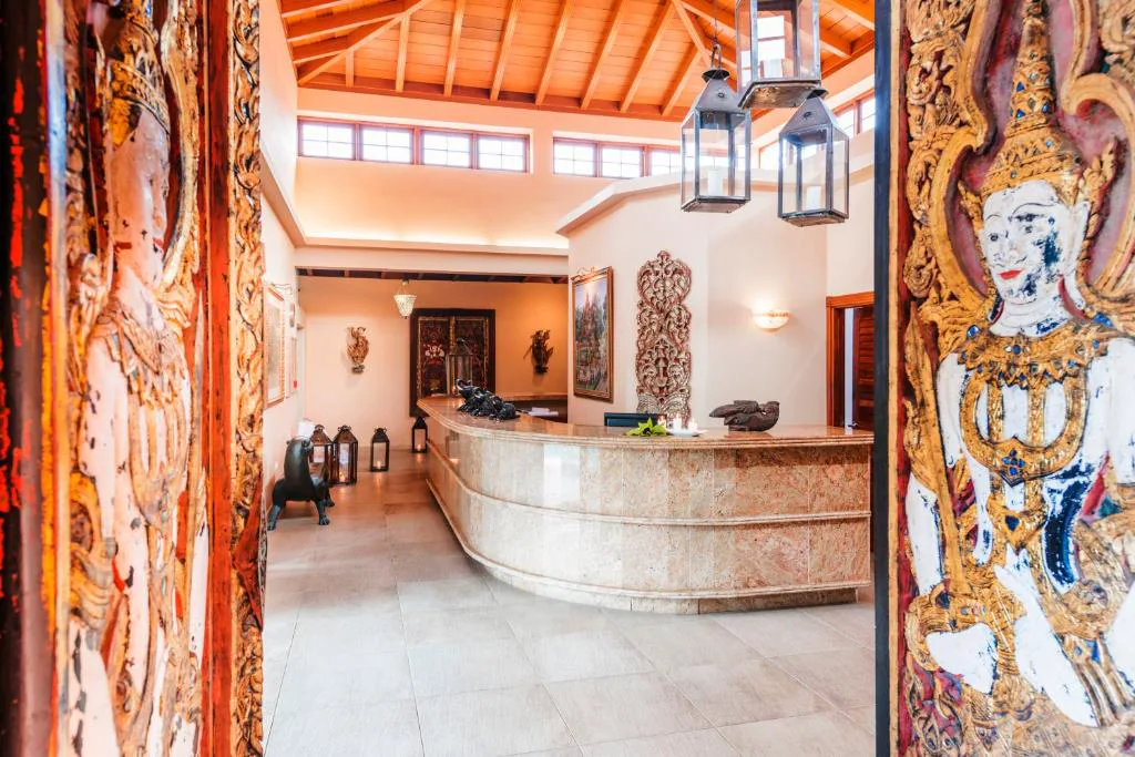 Recepción de estilo oriental con puertas talladas y figuras tailandesas, Hotel Botanico
