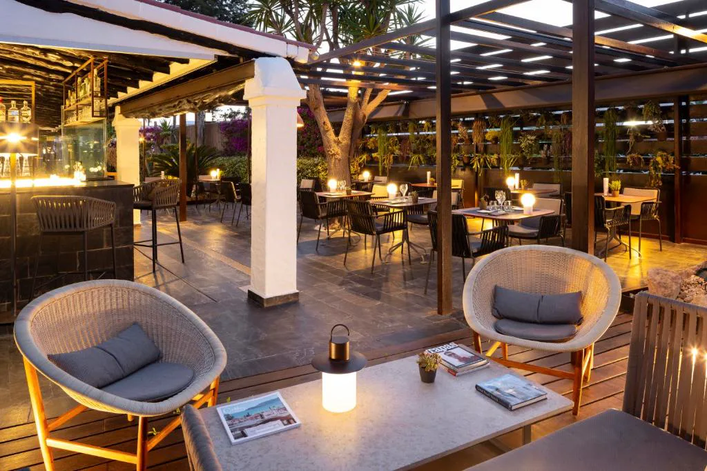 Terraza del restaurante con mesas puestas entre plantas colgantes al atardecer, Ses Pitreras