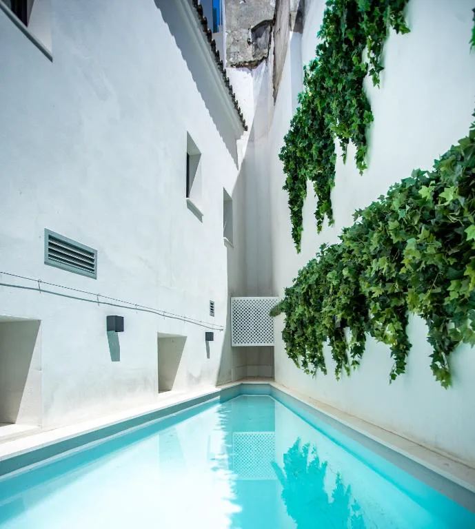 Piscina estrecha entre muros blancos con hiedra