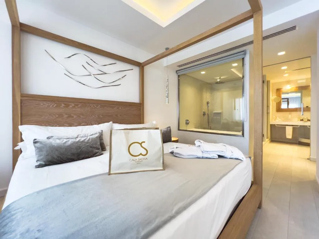 Cama con dosel de madera y baño con ducha de cristal integrado, Hotel Cala Saona & Spa
