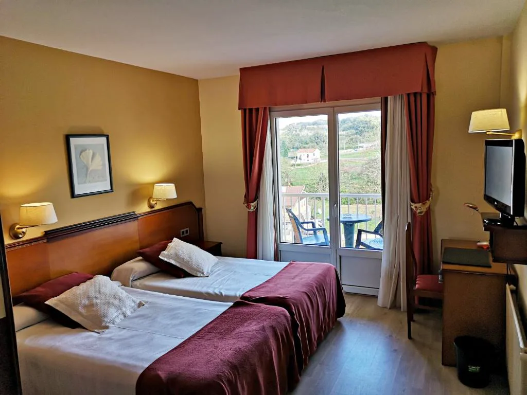 Habitación con dos camas, cortinas rojas y balcón