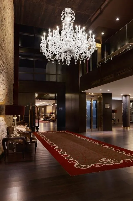 Hall de entrada con lámpara de araña de cristal y alfombra roja bajo el atrio de doble altura