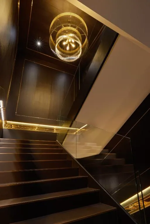 Escalera interior con barandilla de cristal y lámpara dorada de diseño