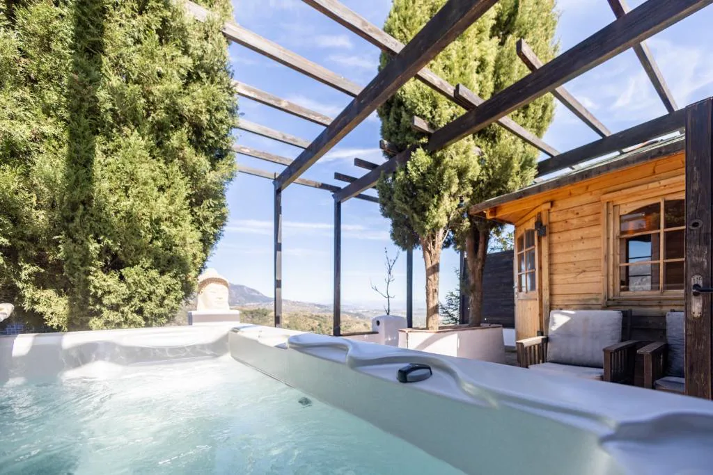 Jacuzzi bajo una cubierta de cristal junto a una cabaña de madera